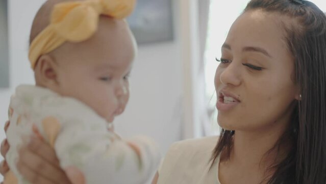 Smiling woman playing with baby daughter at home