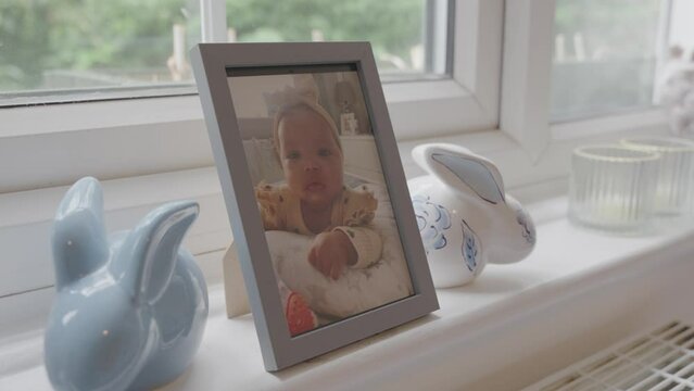 Photography of baby girl and ceramic rabbits on window sill