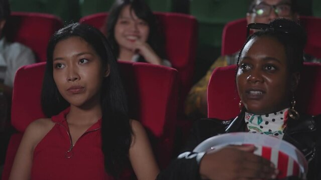 Displeased women the man sitting in the back seat while watching movie in the cinema. A man with inappropriate behavior in the movie theater. Two woman displeased a man kicking seat in movie theater