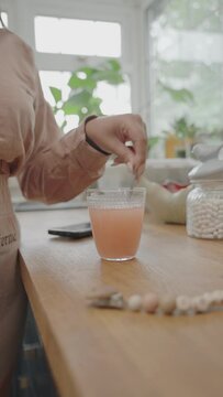 Close-up of woman preparing effervescent tablet in kitchen