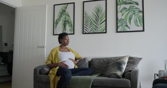 Pregnant woman sitting on sofa at home