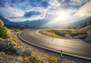 Mountain road at colorful sunset in summer. Dolomites, Italy. Beautiful curved roadway, rocks,...