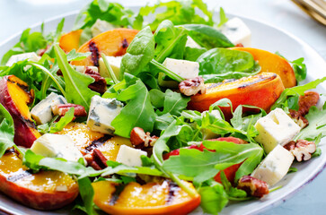 Grilled Peach Salad with Blue Cheese, Pecans and Arugula on Bright Light Blue Background