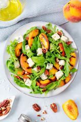Grilled Peach Salad with Blue Cheese, Pecans and Arugula on Bright Light Blue Background