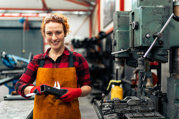 A young woman in STEM measures the dimensions of a metal rod she needs for a project