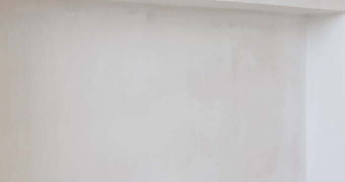 man painting wall in white color with roller
