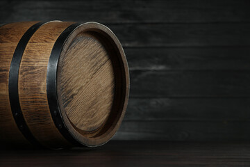 One wooden barrel on table near dark wall, closeup. Space for text