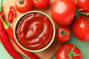 Bowl of tasty ketchup and ingredients on green table, flat lay