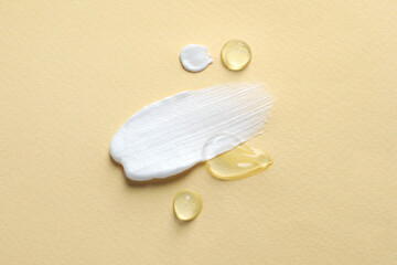 Fototapeta na wymiar Samples of transparent gel and white cream on yellow background, flat lay