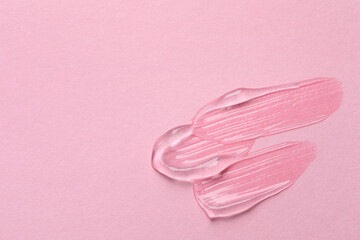 Swatches of cosmetic gel on pink background, top view. Space for text