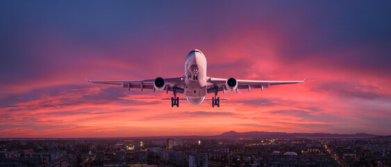 Airplane is flying in colorful sky over the city at night - 638376137