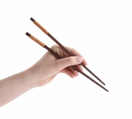 Woman holding pair of wooden chopsticks on white background, closeup