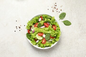 Delicious salad in bowl on light grey table, top view