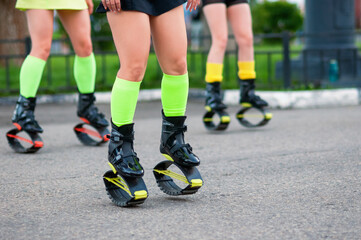 Fototapeta premium A group of sports girls in kangoo jumping boots outdoors. Close-up photo. Bright colors of sportswear. Selective focus.