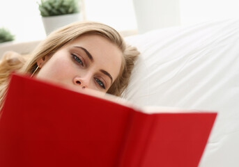 young blond pretty woman read book stay in bed