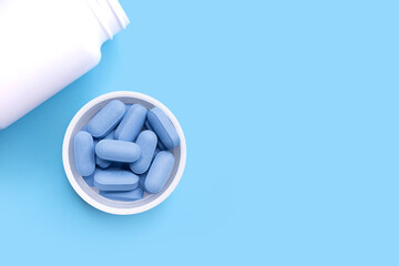 PrEP ( Pre-Exposure Prophylaxis) used to prevent HIV, in plastic pill bottle cap on blue...