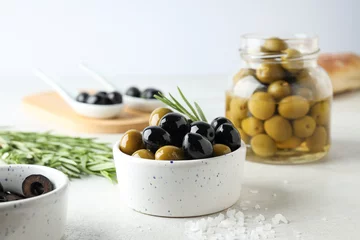 Foto op Plexiglas Olives in bowls and jar on white background, close up © Atlas