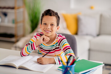 Photo of clever kid learning in modern school interior class writing test copybook sitting desk