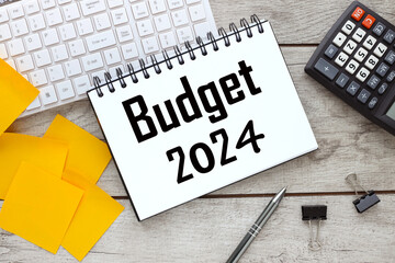 2024 Budget calculator near notepad with text and white keyboard