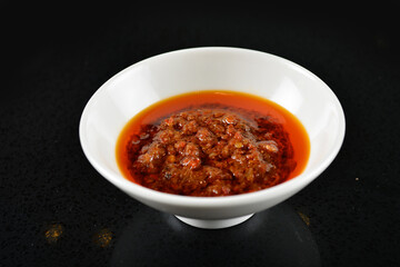 chef signature mala red spicy chilli oil shrimp sambal paste sauce in bowl for laksa on black marble table asian halal food cuisine menu for restaurant