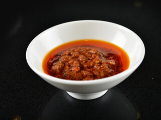 chef signature mala red spicy chilli oil shrimp sambal paste sauce in bowl for laksa on black marble table asian halal food cuisine menu for restaurant