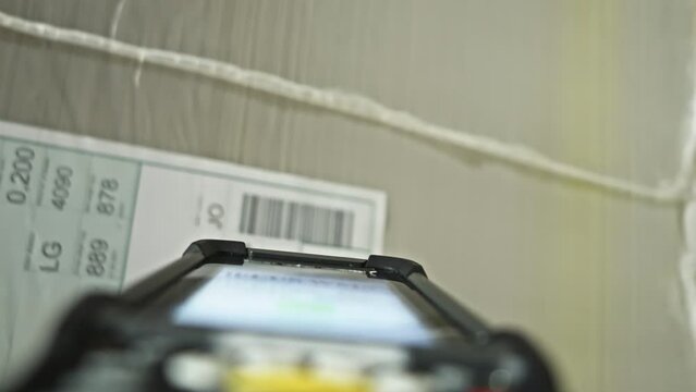 Barcode scanner using on cardboard box in warehouse close up pov. Storehouse employee scanning parcel bar code with handheld reader tool first person view