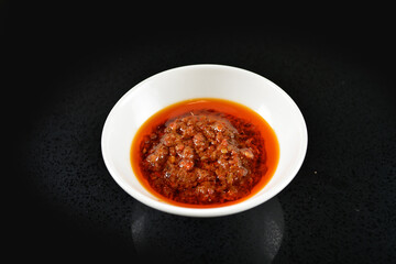 chef signature mala red spicy chilli oil shrimp sambal paste sauce in bowl for laksa on black marble table asian halal food cuisine menu for restaurant