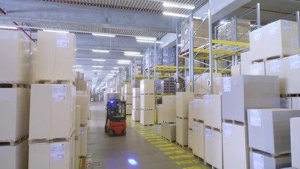 Warehouse forklift driver moving goods cardboard boxes wide shot. Industrial storehouse employee riding in lift truck and loading merchandise parcels