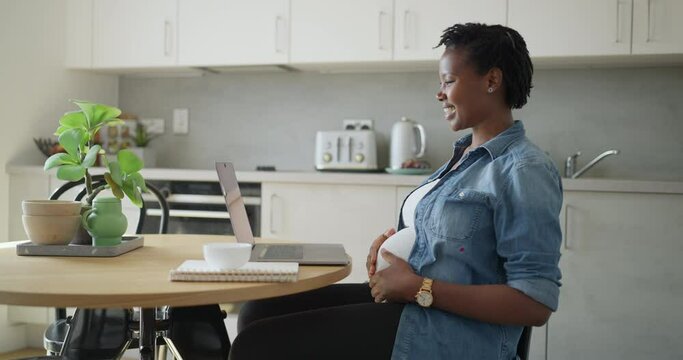 Pregnant woman talking on video call while working in kitchen