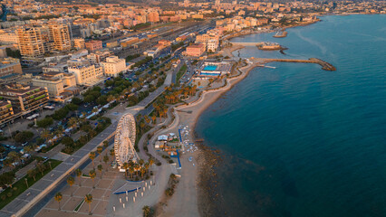 Aerial view of an Italian seaside town. Golden sand and crystalline sea. Ferris wheel and natural...