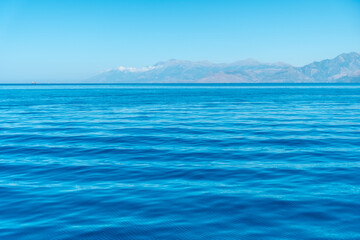 Turquoise sea water texture with sun rays in the mediterranean sea and sky background