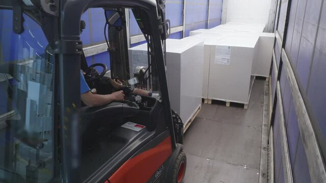 Logistics storehouse forklift loading boxes in shipment truck for transportation, view from inside trunk container. Warehouse loader putting heavy goods parcels in trailer vehicle