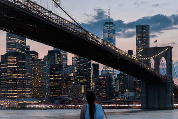 Tourist girl in New York City at Night skyline, skyscrapers, Brooklyn Bridge, Manhattan, Downtown, USA