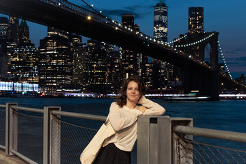Happy tourist girl in New York City at Night skyline, skyscrapers, Brooklyn Bridge, Manhattan, Downtown, USA