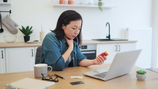 Female touching sick throat while working remotely from home