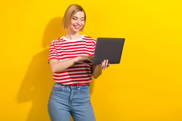 Photo of lovely positive successful girl wear stylish clothes typing sending letter modern device isolated on yellow color background