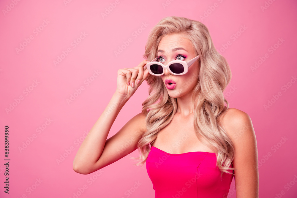 Wall mural Photo of cute nice impressed girl hand touch sunglass pouted lips look empty space isolated on pink color background