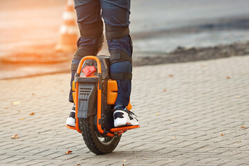 Electric unicycle. Man rides on electric mono wheel down the city street. Man cycling on monowheel in protective gear. Boy rides on single wheel. © Tricky Shark