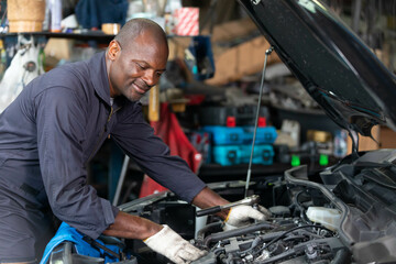 Fototapeta na wymiar African mechanic worker checking and fixing a car in garage