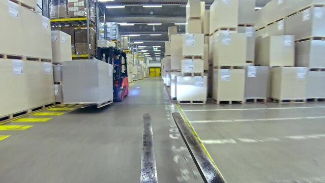 Forklift driving in logistics and distribution center, sorting packages pov. Warehouse lift truck transporting and sorting goods first person view