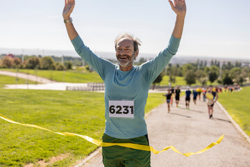 senior runner with bib number winning a marathon race outdoors