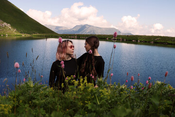 A couple of female travelers. Romantic date in nature. A lesbian couple is traveling among the mountains. Hikers by the lake surrounded by flowers