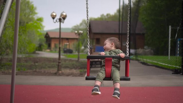A happy one year old boy swings on a swing