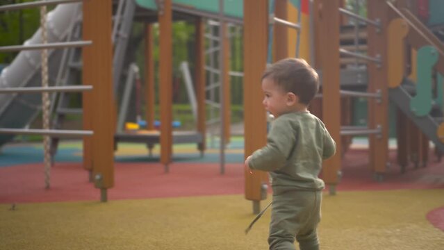 A two-year-old child walks on a playground