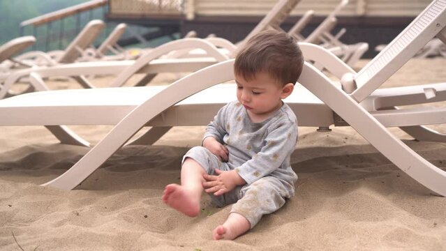 A little boy sits on the beach by the river