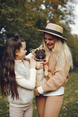 Mother and her daughter with a little puppy french bulldog in a park