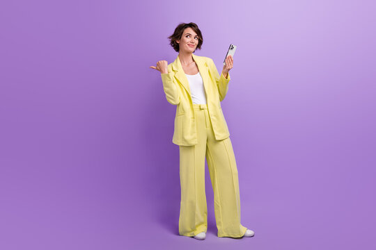 Full length photo of cute thoughtful lady wear suit blazer typing modern device thumb empty space isolated violet color background