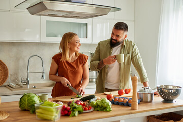 Affectionate couple cutting vegetable in the kitchen