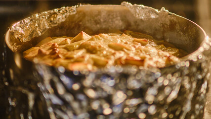 Apple pie in a baking dish cooking in the oven