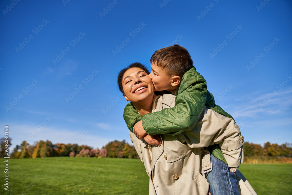 Wall mural cute boy kissing cheek of mom, african american family, having fun together, love, bonding concept